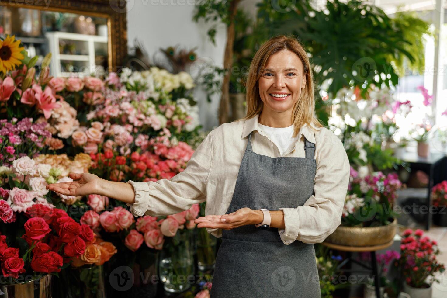 Smiling woman florist small business owner standing in own floral store and waiting for client photo