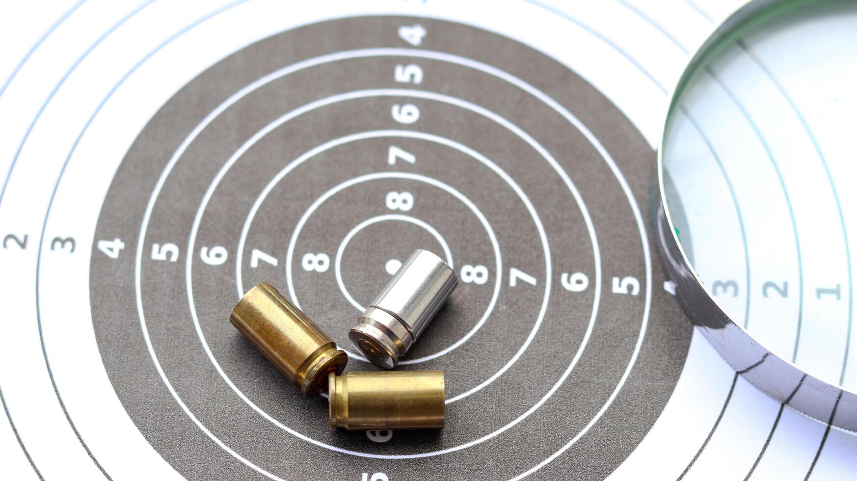 Empty bullet casing on a shooting target, with a part of magnifying glass, evoking the concept of crime scene investigation and unraveling mysteries. photo
