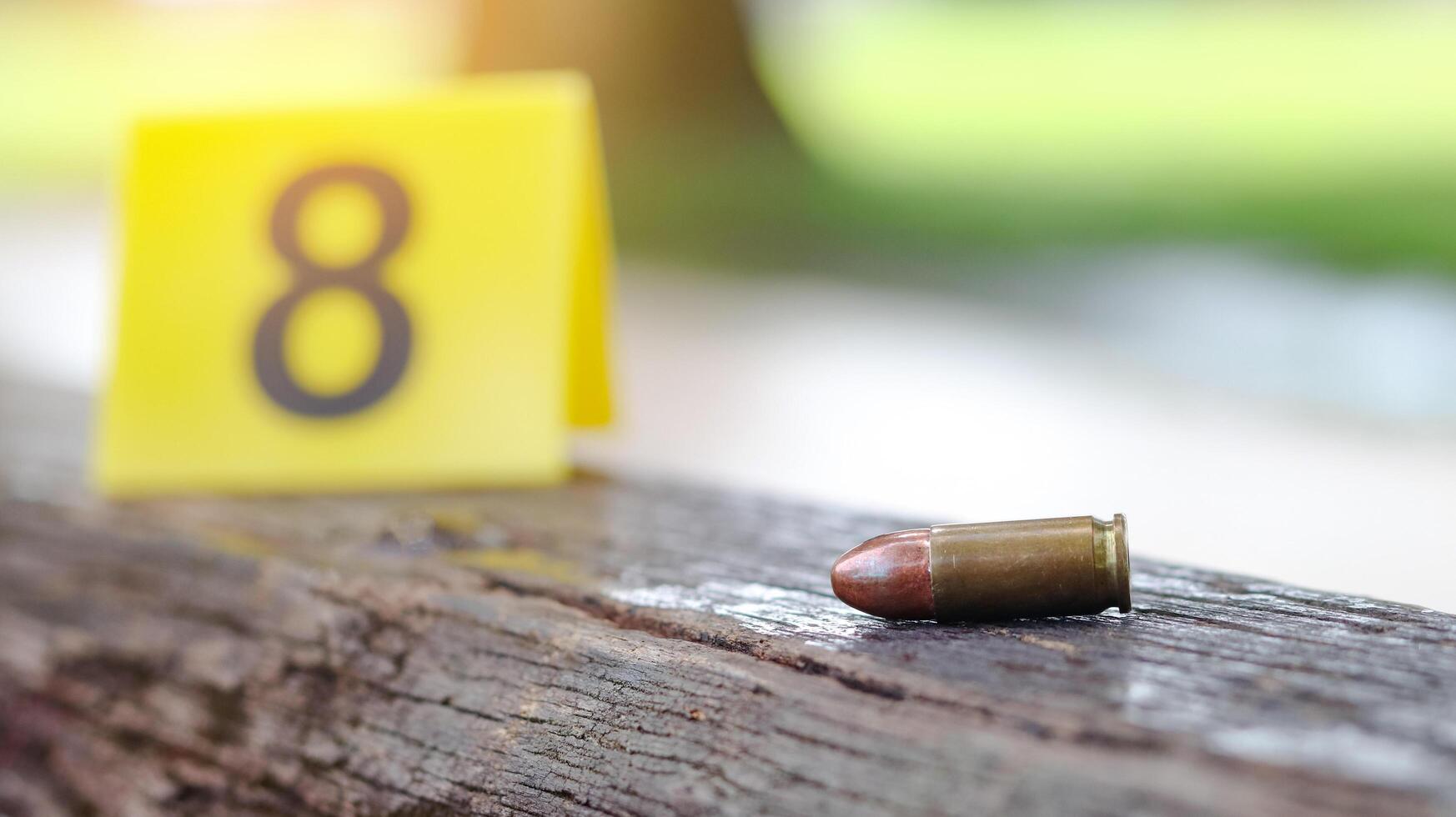 9 mm pistol bullet lying on dark wooden bench with blur number 8 sign on blur background. Concepts of criminal investigations and shooting sport. photo