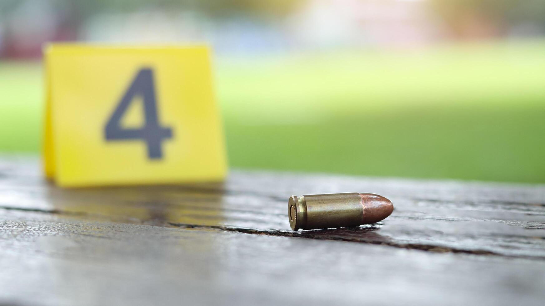 9 mm pistol bullet lying on dark wooden bench with blur number 4 sign on blur background. Concepts of criminal investigations and shooting sport. photo