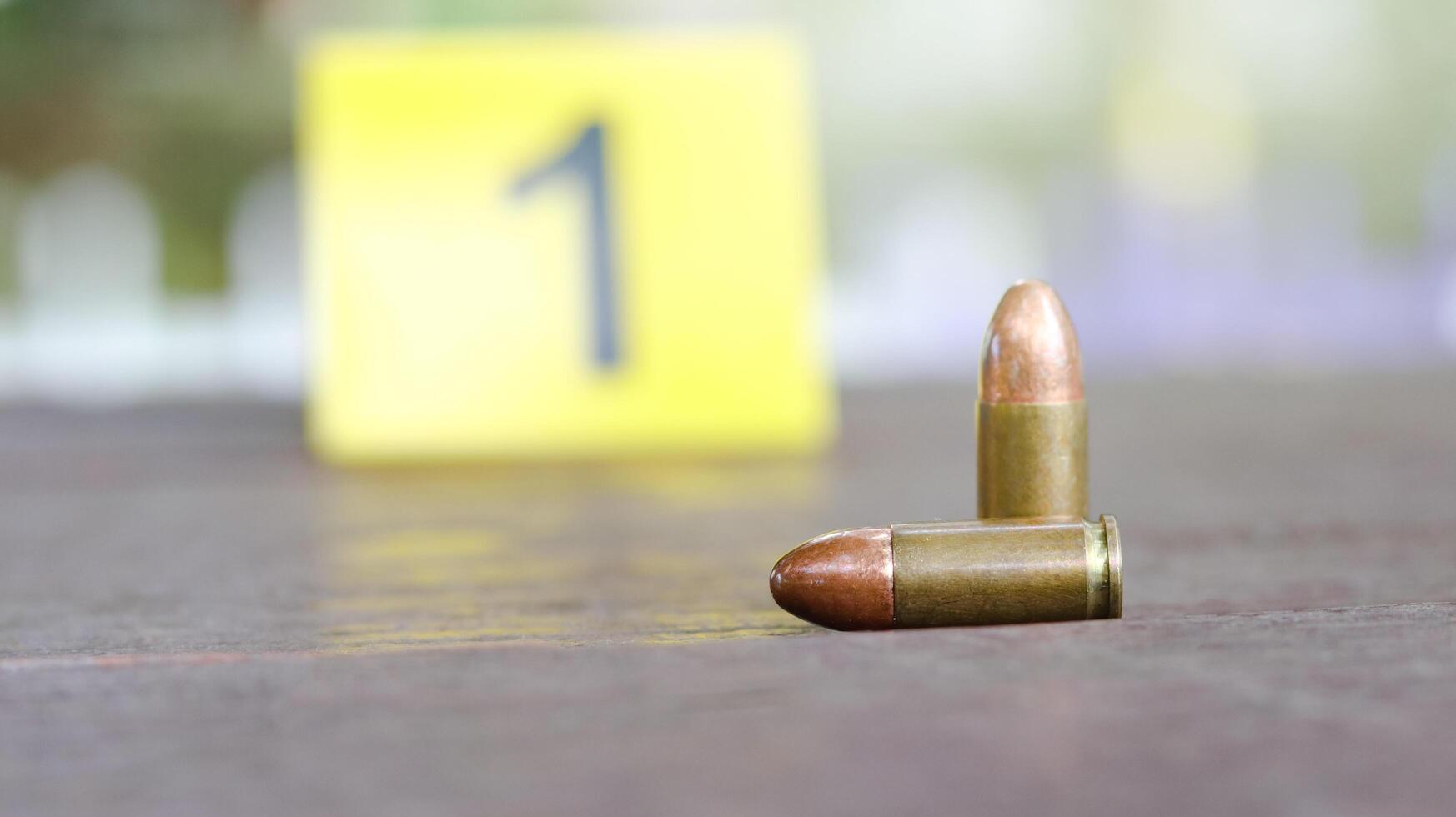 9 mm pistol bullet lying on dark wooden bench with blur number 1 sign on blur background. Concepts of criminal investigations and shooting sport. photo