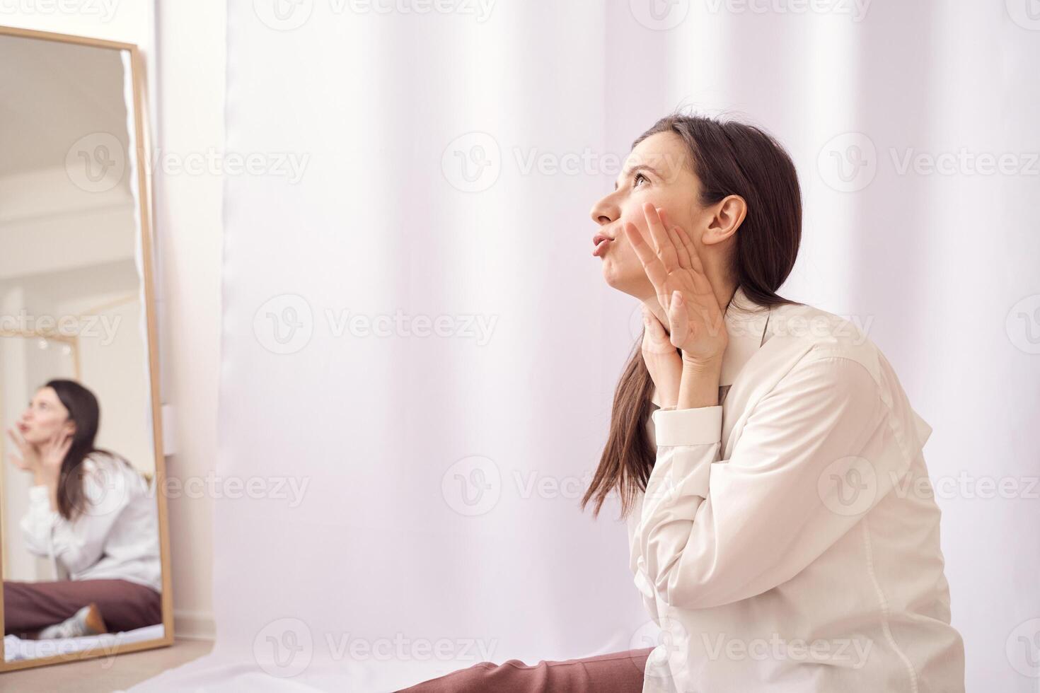 Woman practicing affirmations in front of mirror for self-confidence and positivity in bright minimalist room. photo