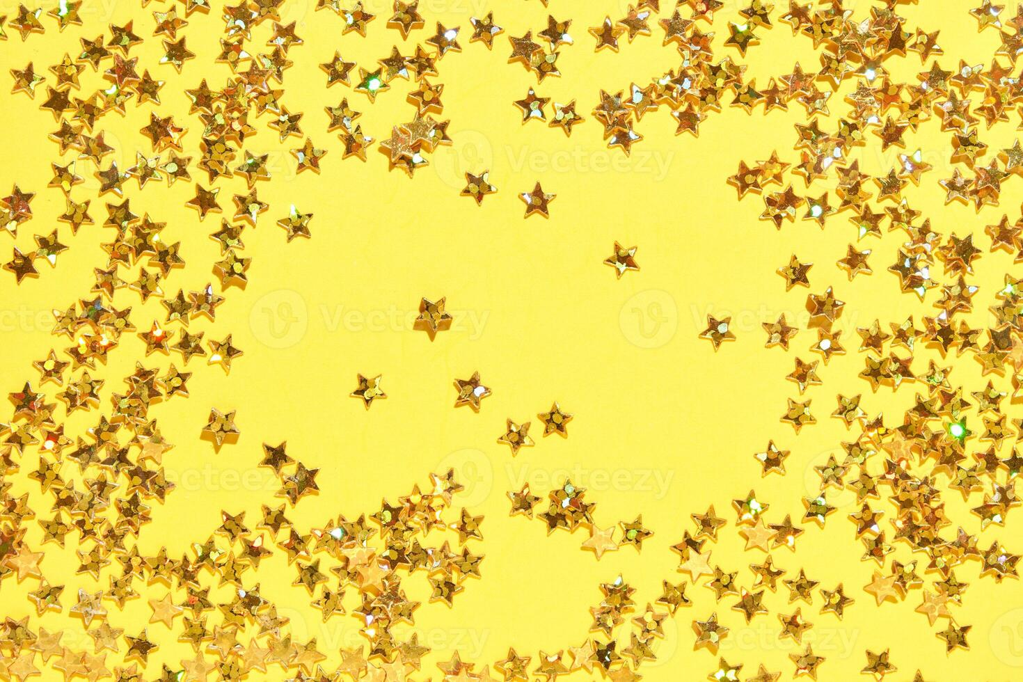 Sparkling gold star confetti on yellow background for festive and celebration themes. photo