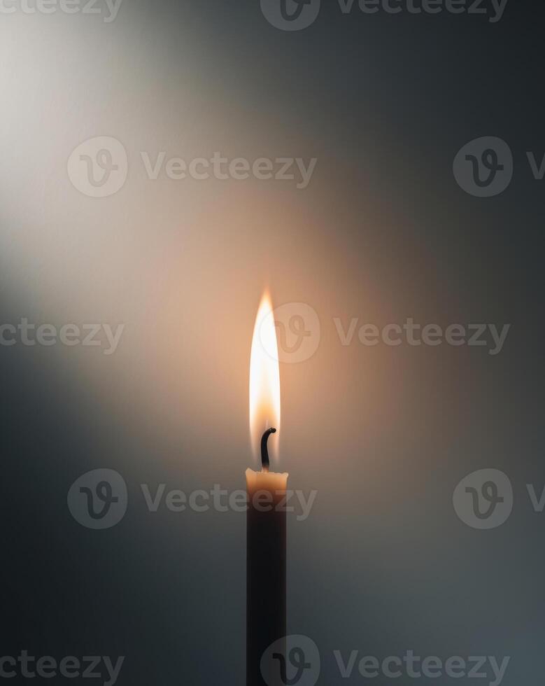 A single candle is lit in the dark photo