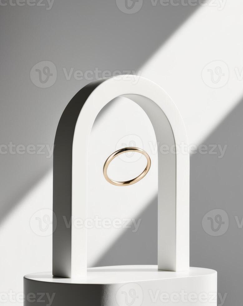 A white pedestal with a gold ring sits beneath a white circular arch. photo