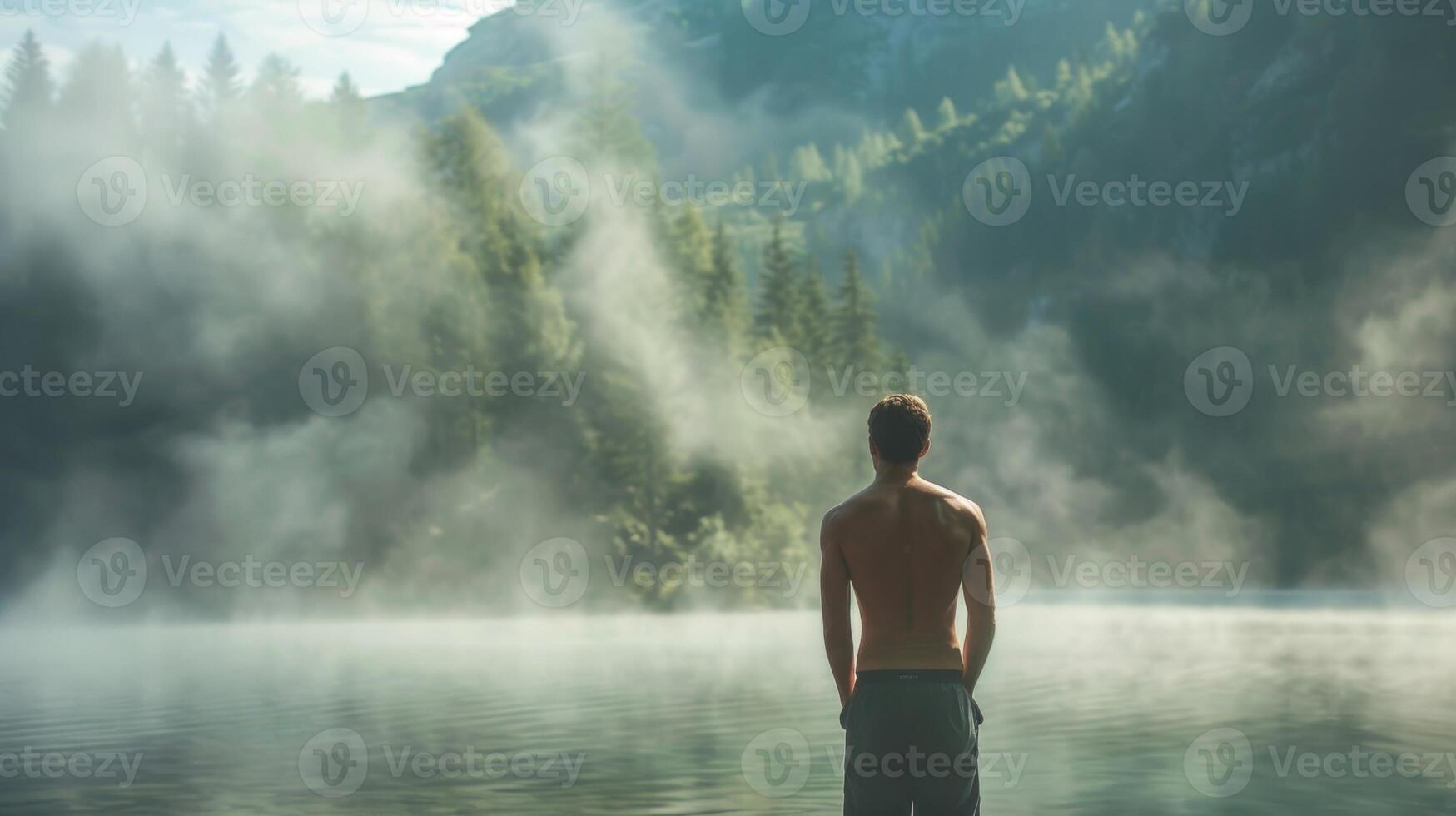 A man standing in front of a foggy lake preparing for his morning routine with a round of deep breaths photo