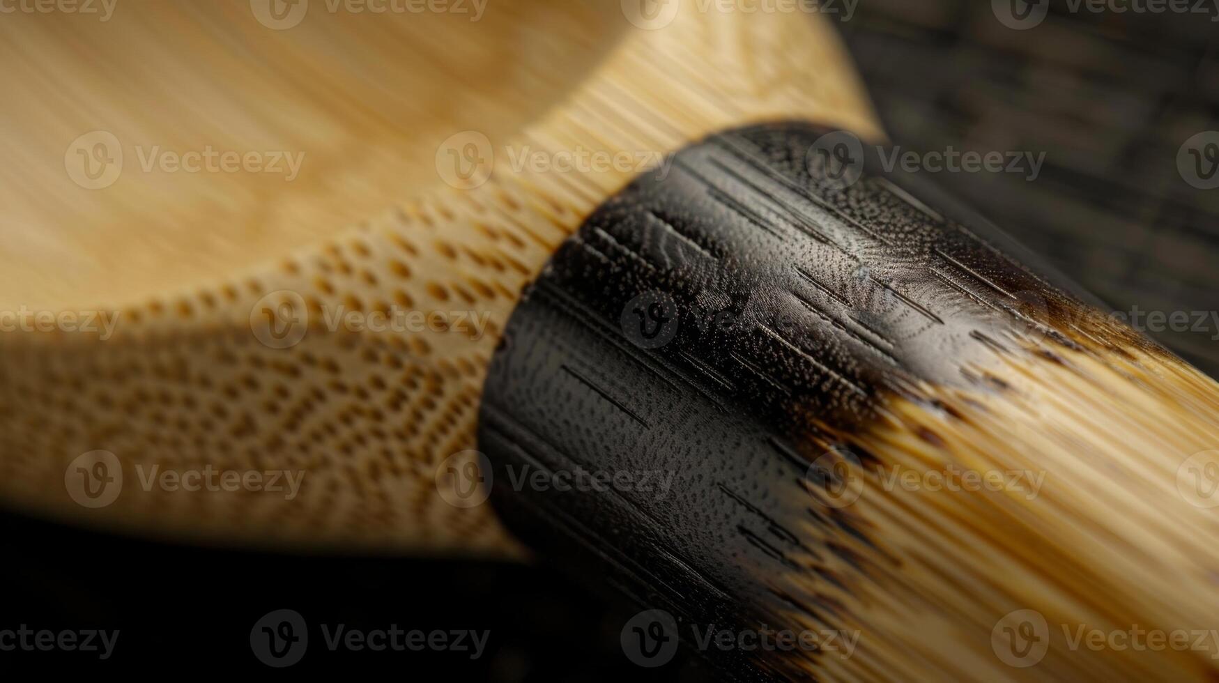 An upclose view of a bamboo ladle displaying the varying shades of the grain from light to dark. The handle has a ribbed texture for a comfortable grip photo