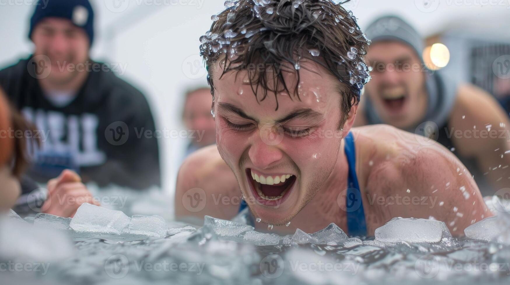 A man grimacing as he sinks into a large tub of ice cubes his friends cheering him on from the side for the winter ice bath challenge photo
