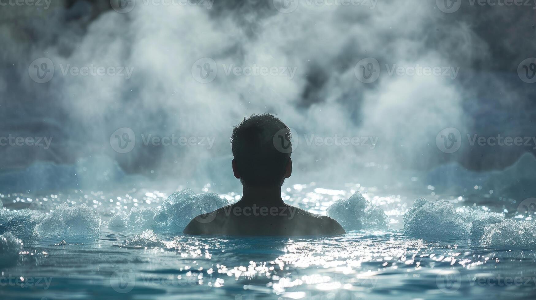 A person sitting in an ice bath their breath visible in the cold air as they try to relax and embrace the freezing temperatures photo