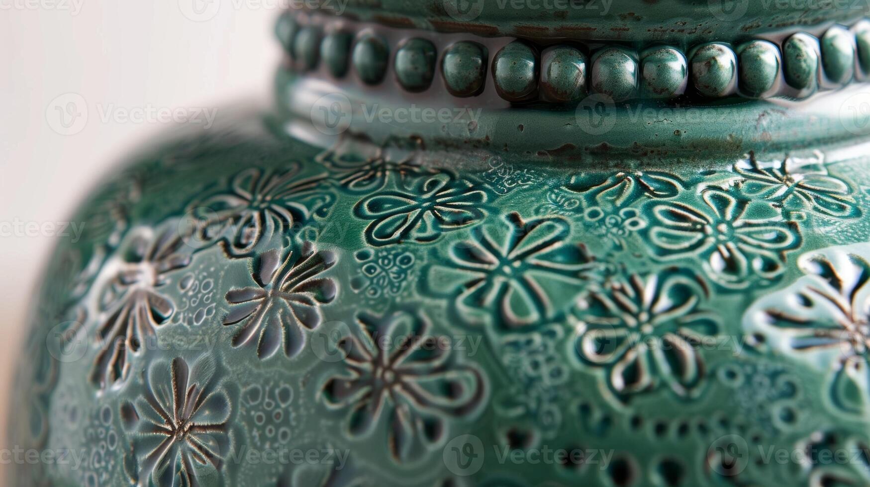 The intricate handcarved details on a ceramic vase featuring a glossy emerald green glaze that adds a touch of elegance to any room photo