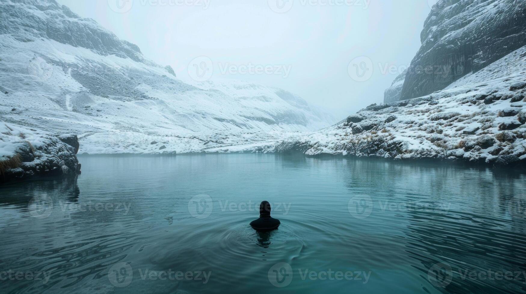 A lone figure submerged in a freezing mountain stream their breath visible in the cold air photo