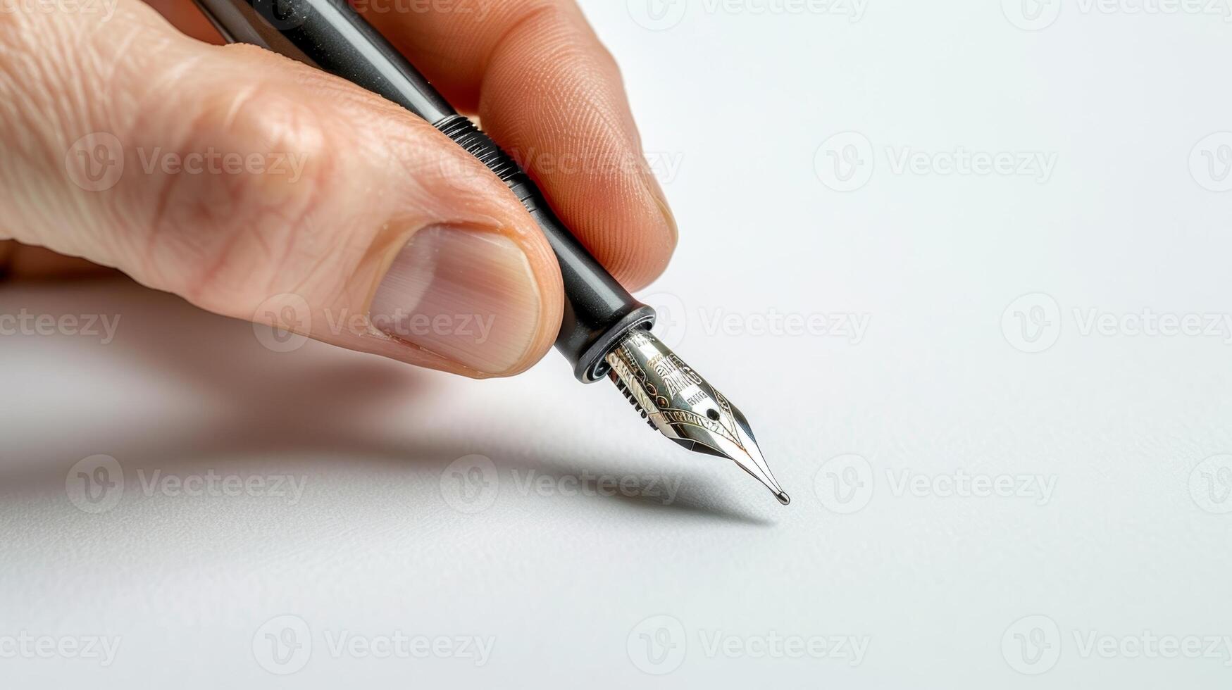 A hand holding a classic fountain pen poised over a blank page capturing the anticipation and creative potential of this writing tool photo