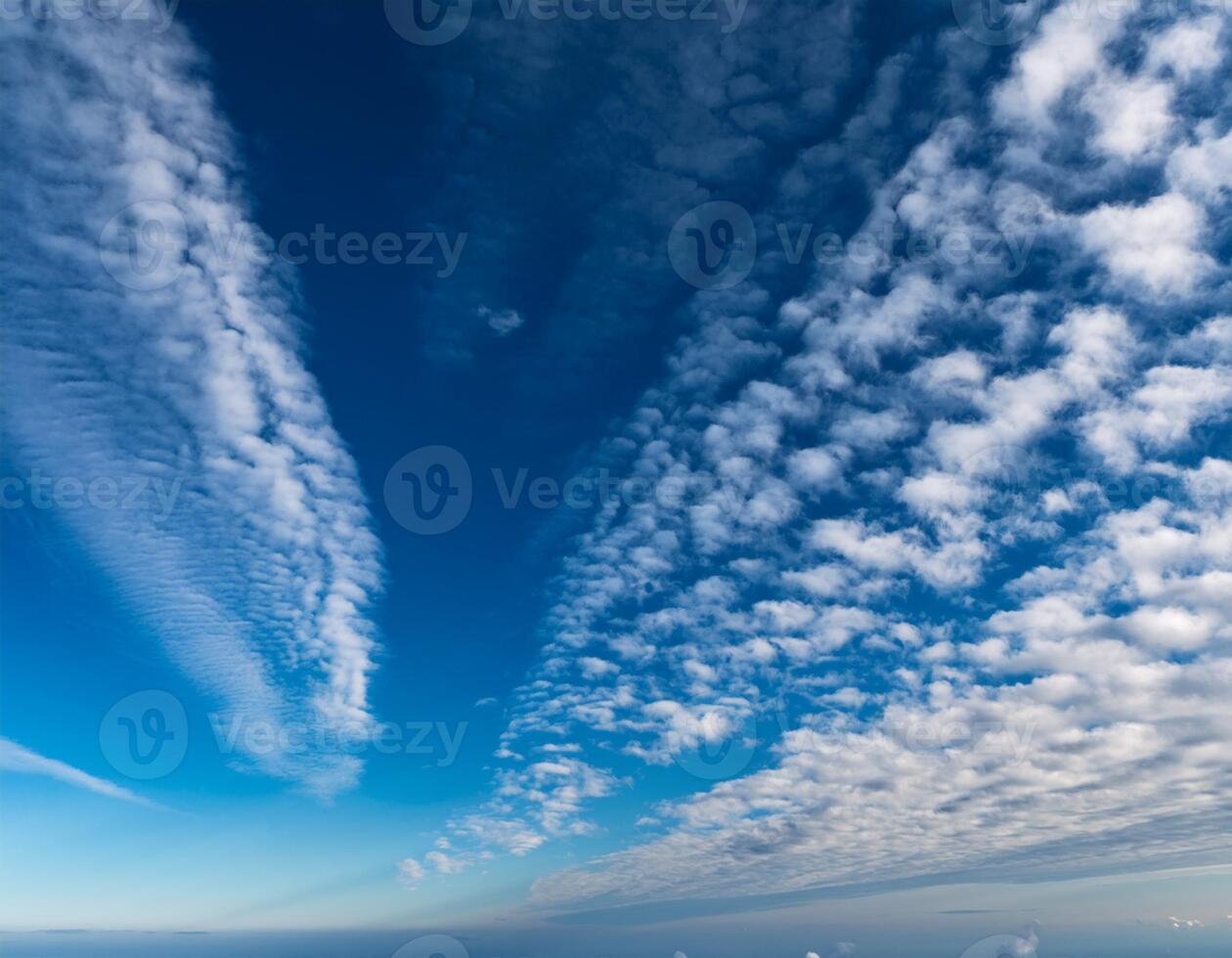 Vivid blue sky filled with unique, textured cloud formations creating a dramatic and expansive natural pattern above the horizon. photo
