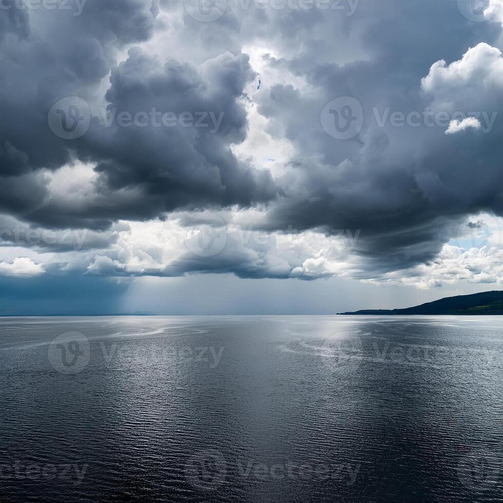 Dramatic dark storm clouds hover over calm ocean waters, creating a moody and serene seascape with distant land on the horizon. photo