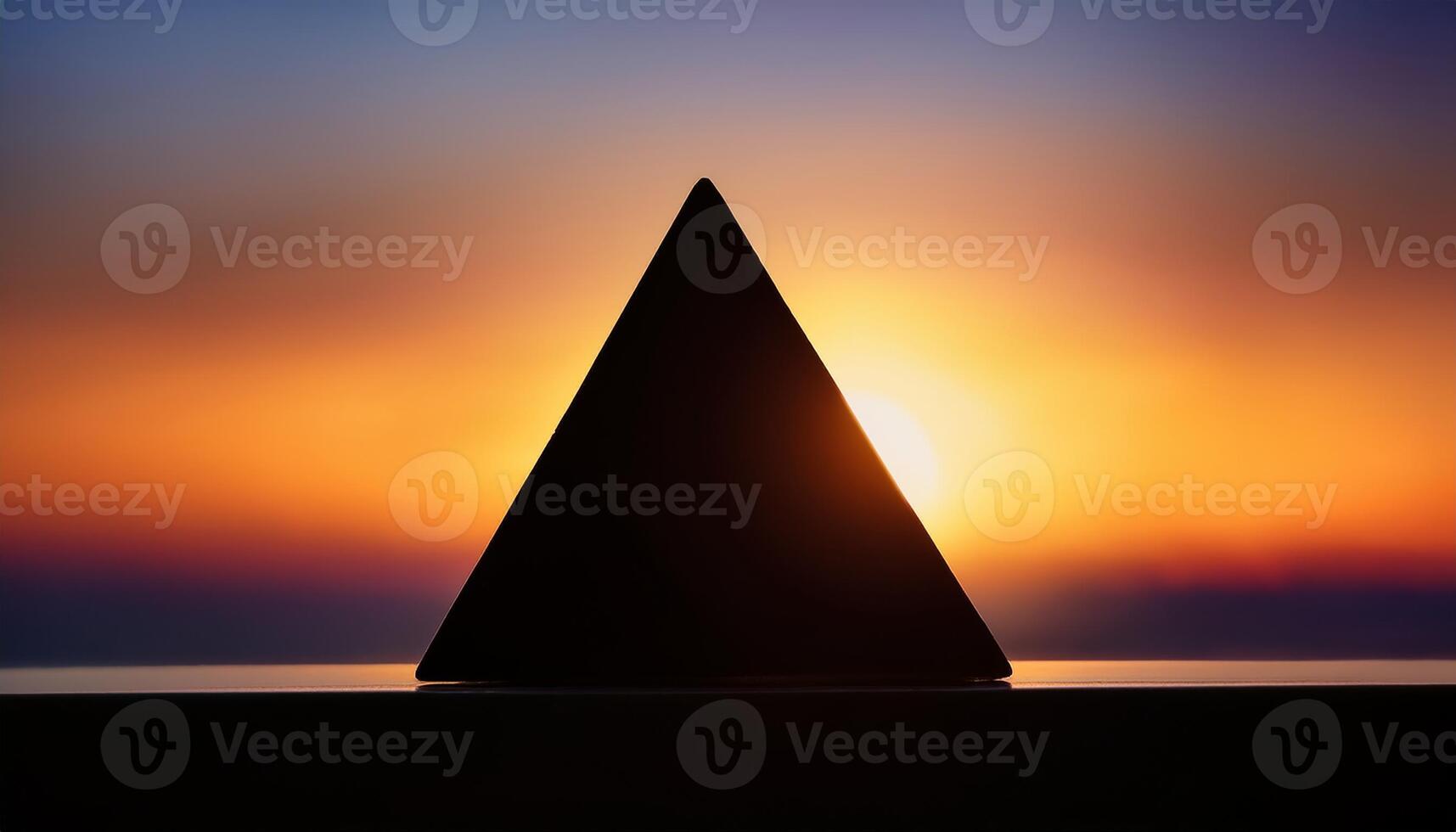 Geometric pyramid silhouette framed by a glowing sunset, creating a striking contrast between the dark shape and colorful sky. photo