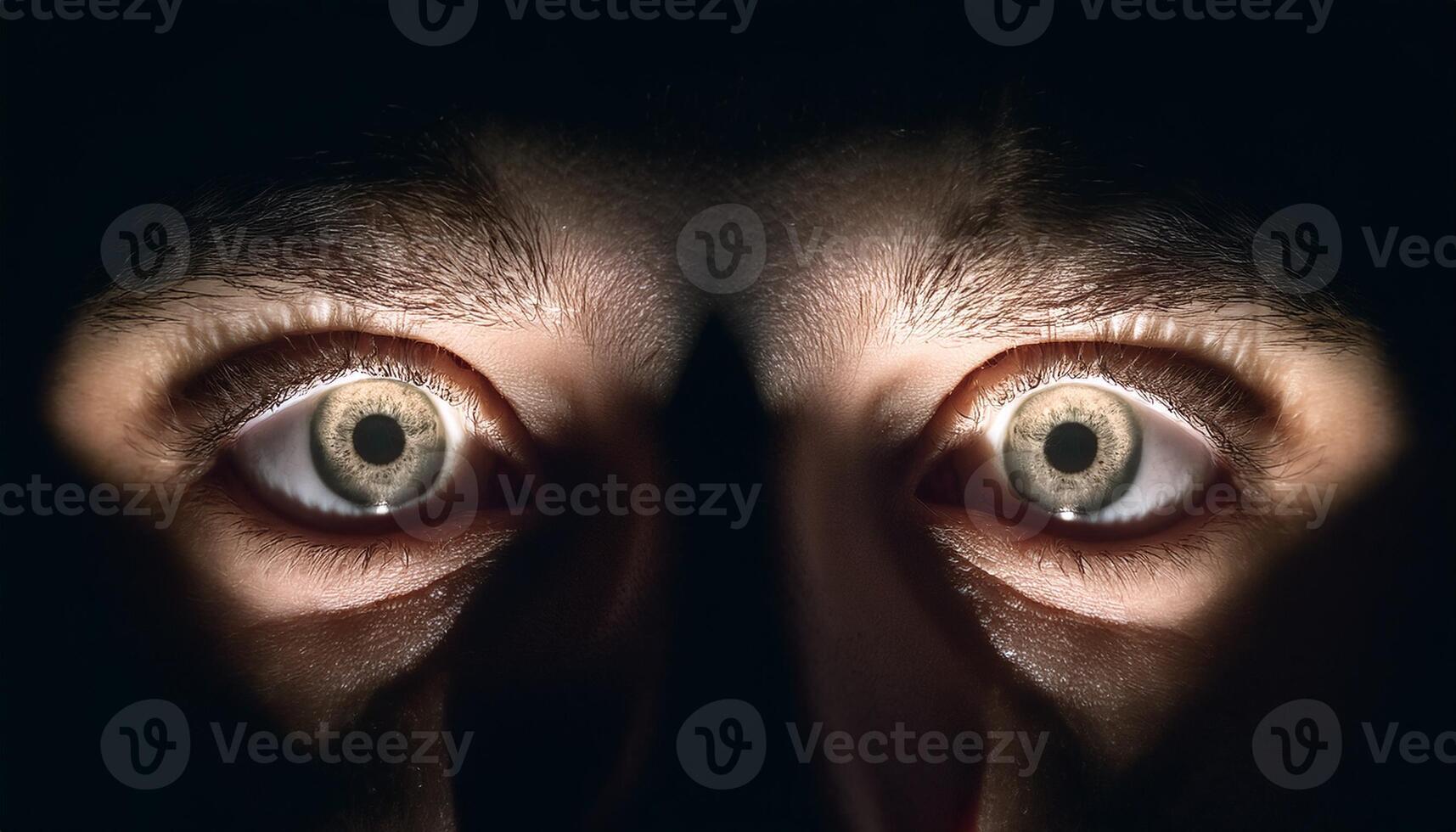 Close-up of a person's intense, wide-open eyes illuminated by dramatic lighting, creating a sense of fear, surprise, or curiosity. photo