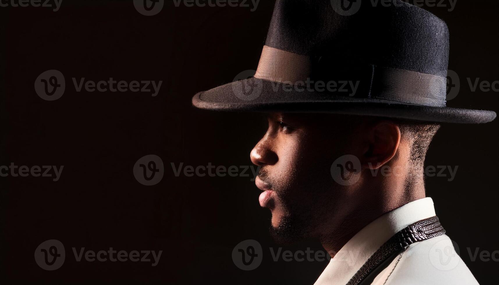 Close-up side profile of a man wearing a classic fedora hat and formal attire, set against a dark background for a vintage look. photo