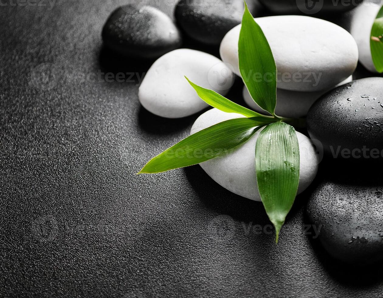 Black and white smooth stones with fresh green bamboo leaves on a textured dark surface, symbolizing peace and balance. photo