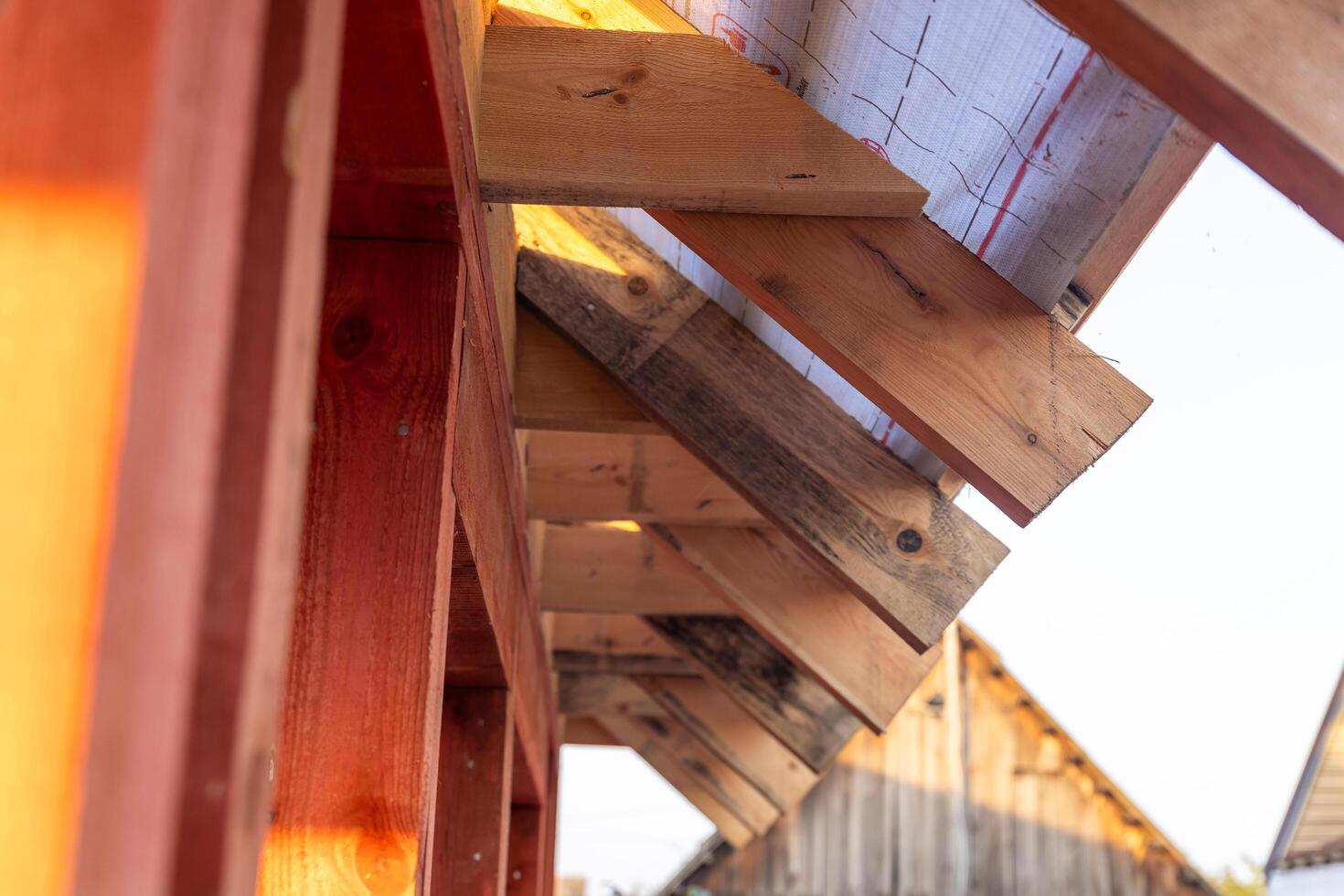 lose-up of a wooden roof frame during construction. The wooden planks are arranged in a grid pattern and supported by beams, creating a sturdy foundation for the roof. photo