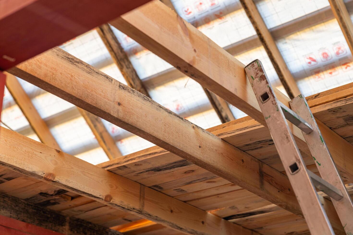 lose-up of a wooden roof frame during construction. The wooden planks are arranged in a grid pattern and supported by beams, creating a sturdy foundation for the roof. photo