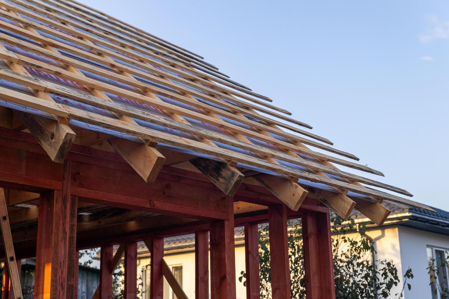 lose-up of a wooden roof frame during construction. The wooden planks are arranged in a grid pattern and supported by beams, creating a sturdy foundation for the roof. photo