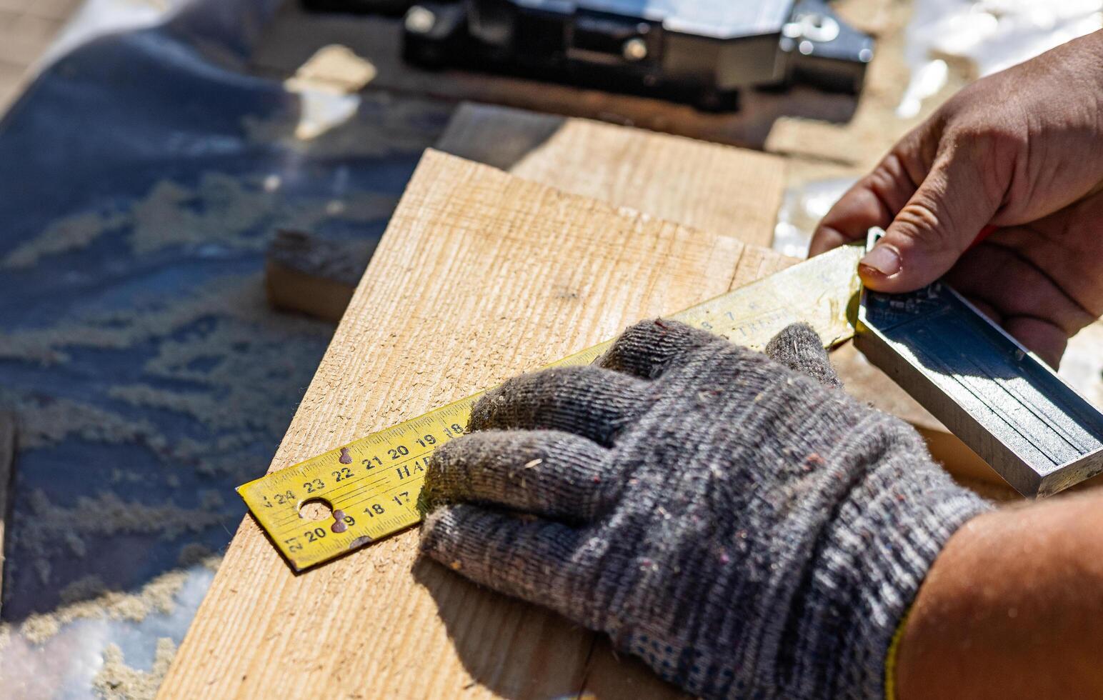 Yellow ruler placed on a wooden beam. Tools are being used to measure and mark the wooden beam for cutting or construction. The close-up view of the tools and the wooden beam. photo