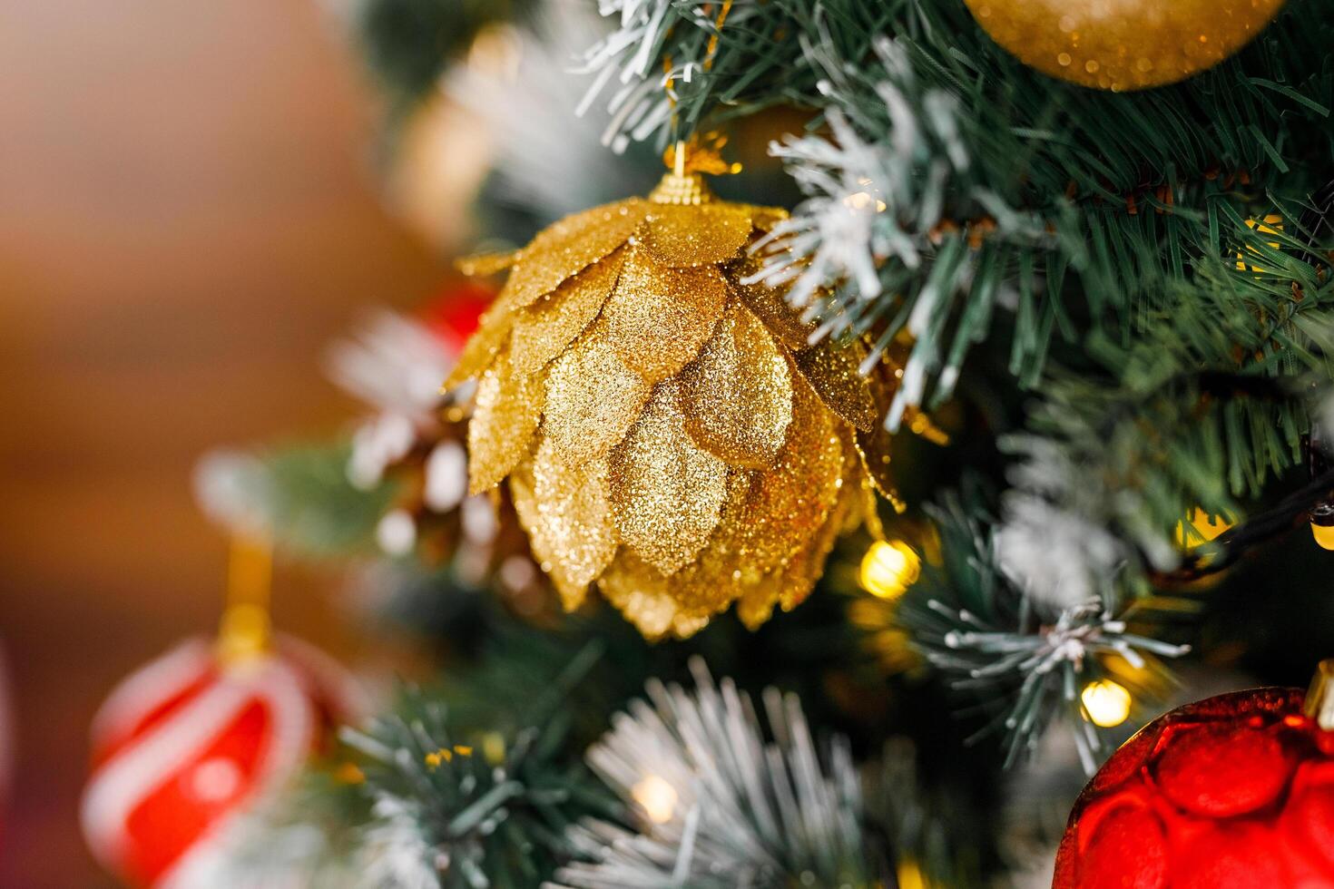 A close-up of a gold pinecone-shaped ornament on a Christmas tree photo