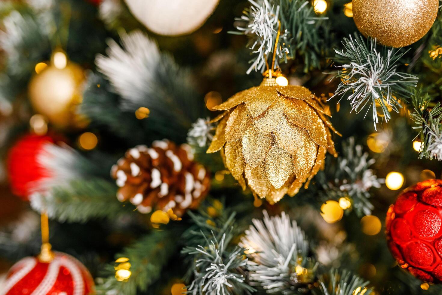 A close-up of a gold pinecone-shaped ornament on a Christmas tree photo