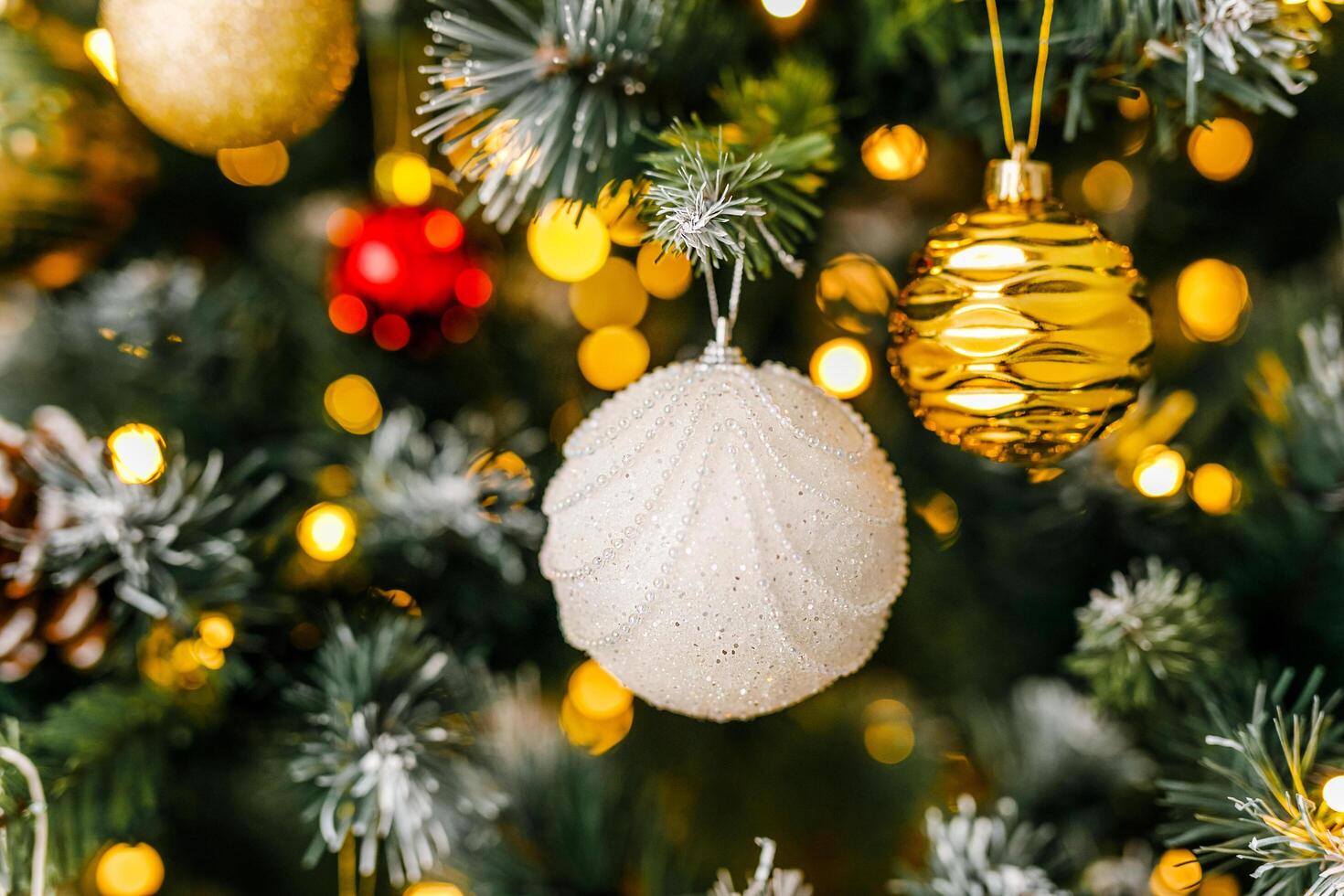 A close-up of a white glittering decoration on a branch of a Christmas tree photo