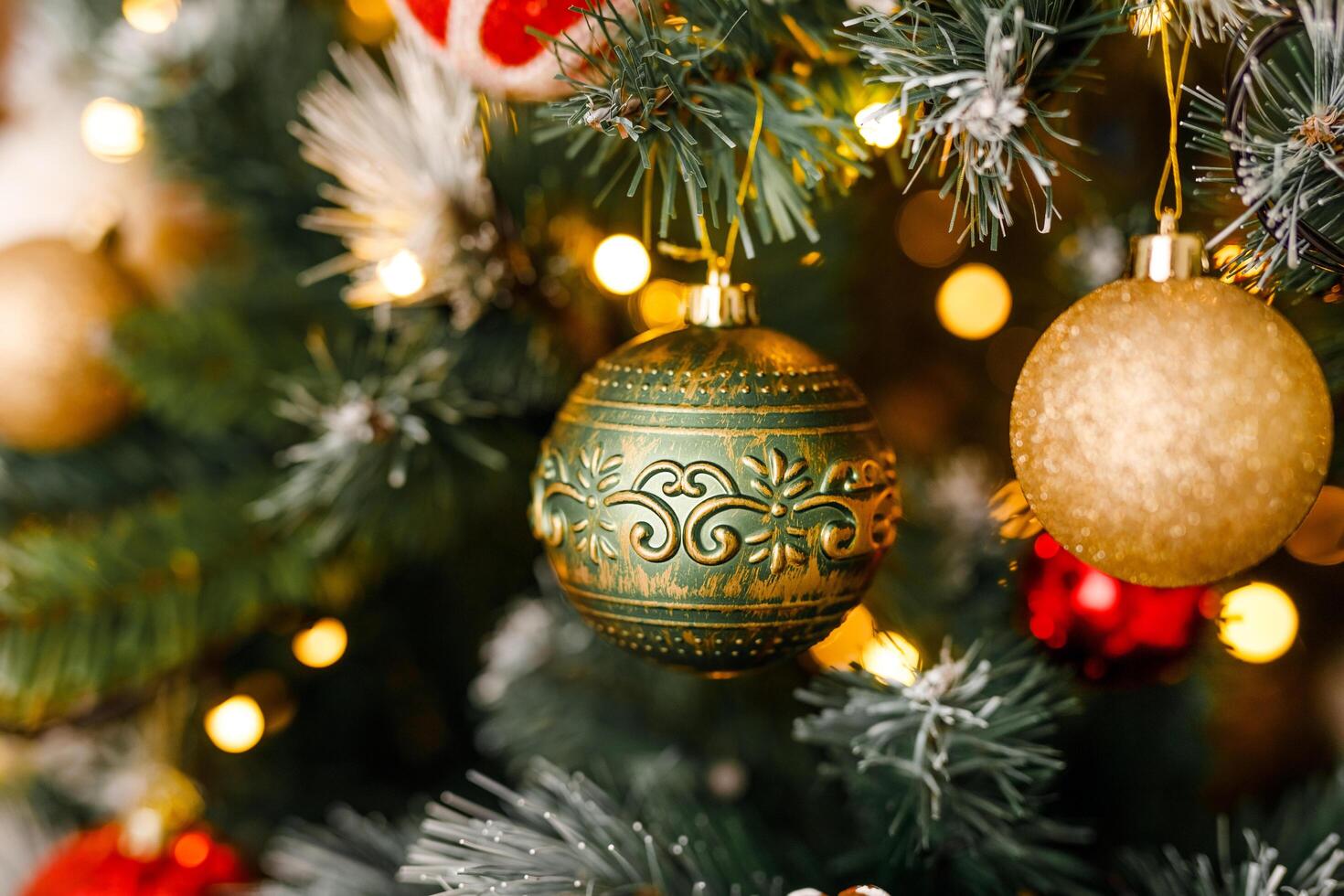 A close-up of gold and green glittering ornaments on a branch of a Christmas tree photo