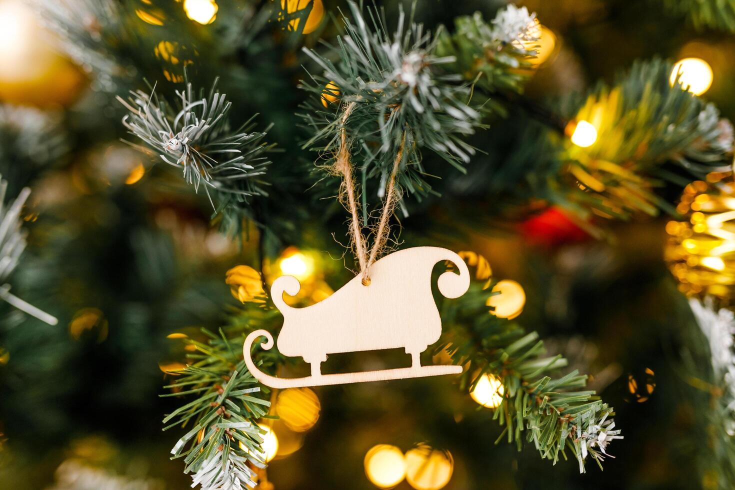 A close-up of a wooden sled decoration on a branch of a Christmas tree photo