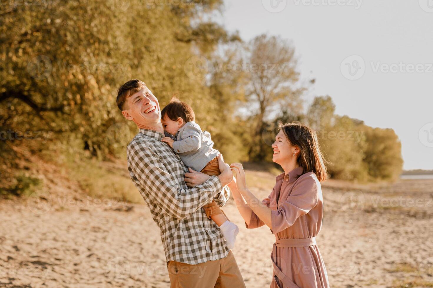 Happy family walking on the road in the park. Father, mother holding baby son on hands and going together. Rear view. Family Ties concept. photo