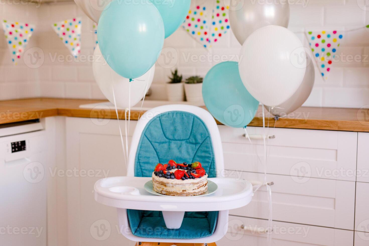 Children's high chair is decorated with blue and white balls to celebrate the first birthday photo