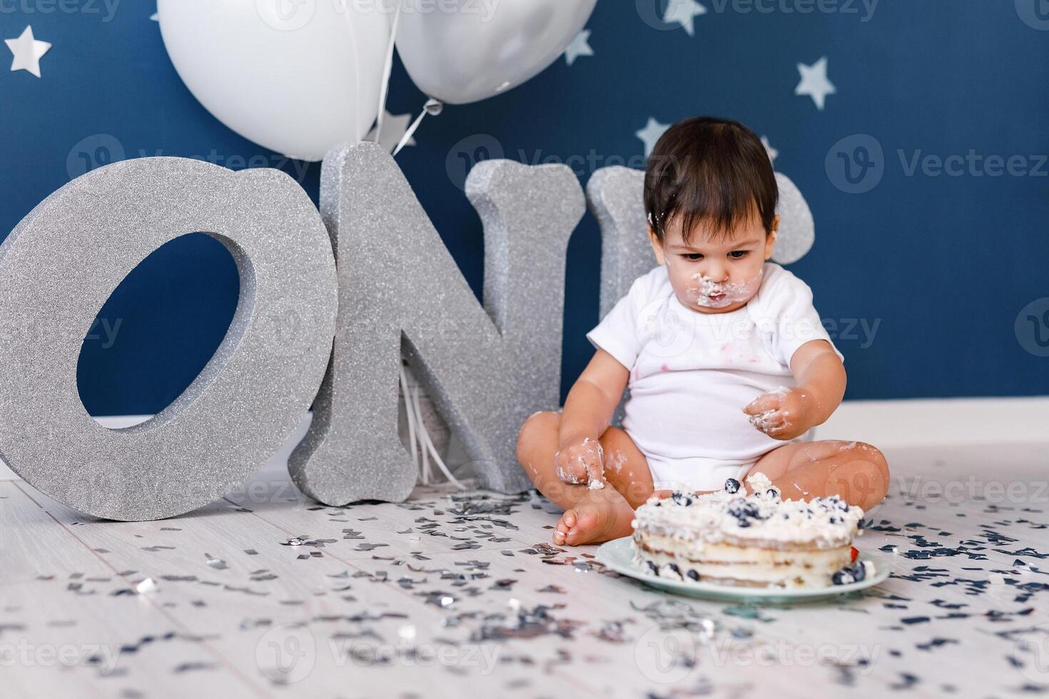 curious baby boy poking finger in his first birthday cake photo