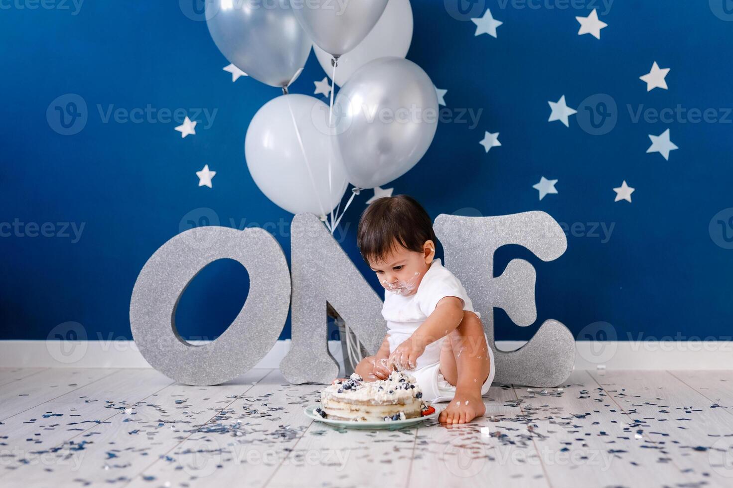 curious baby boy poking finger in his first birthday cake photo