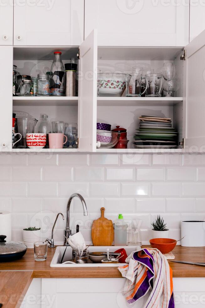 Clutter, dirty dishes by the sink in the white kitchen photo