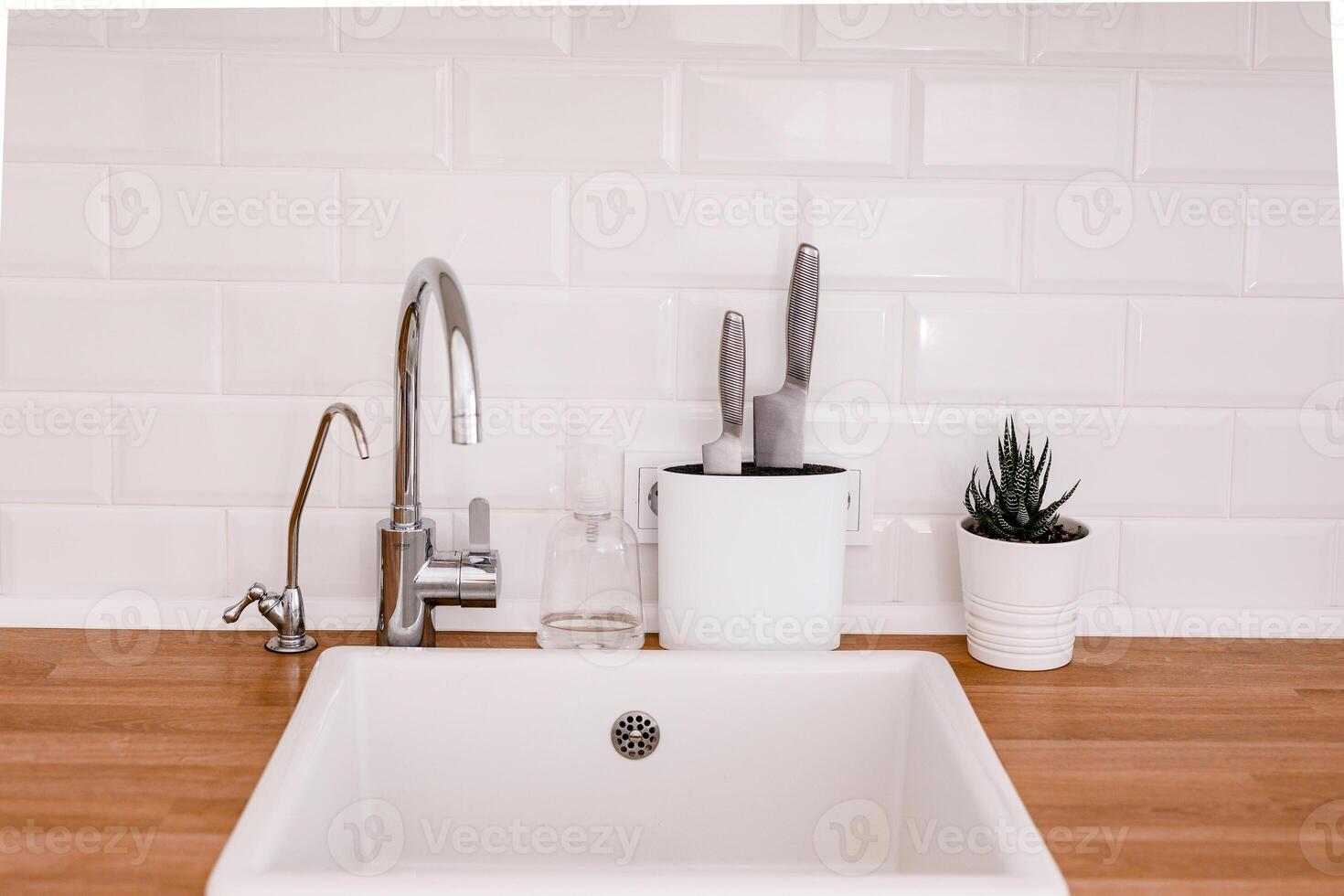 Clean white sink on wooden table in white kitchen photo