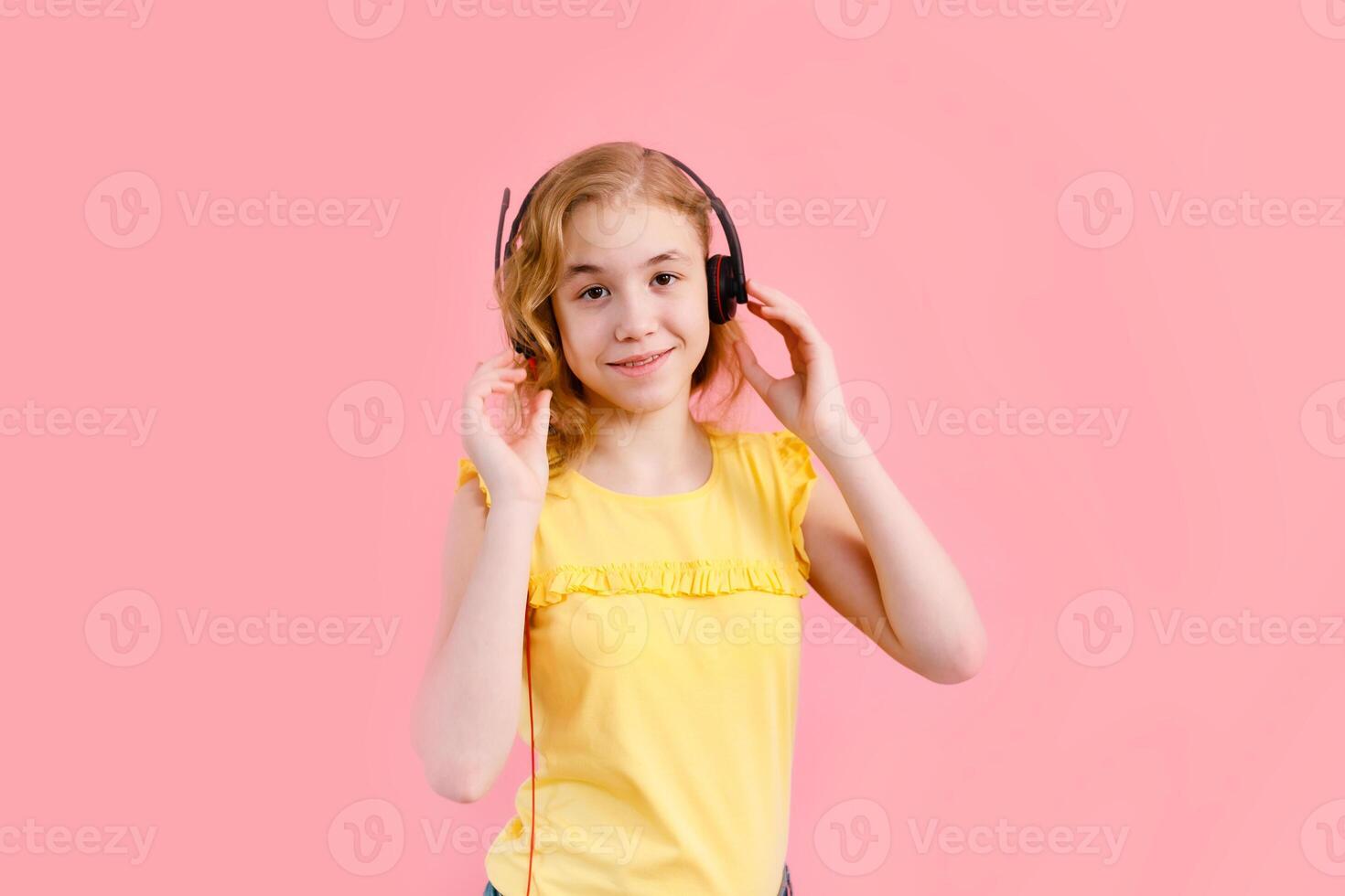 Girl studying homework with tablet pc and earphones during his online lesson at home, social distance during quarantine. Pink background with free space for text photo