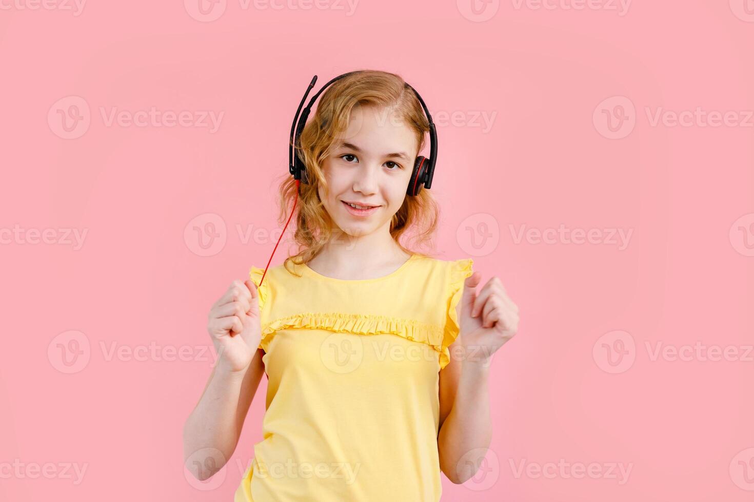 Girl studying homework with tablet pc and earphones during his online lesson at home, social distance during quarantine. Pink background with free space for text photo