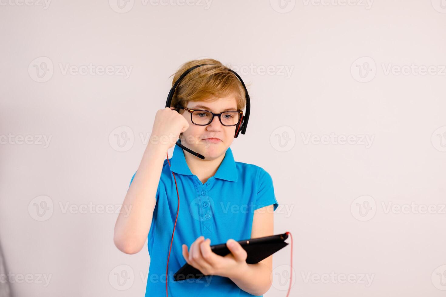 Little boy in glasses using a tablet computer with a light background photo