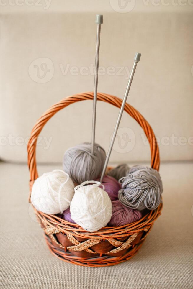 Close-up of colorful wool balls and giant knitting needles in a basket photo