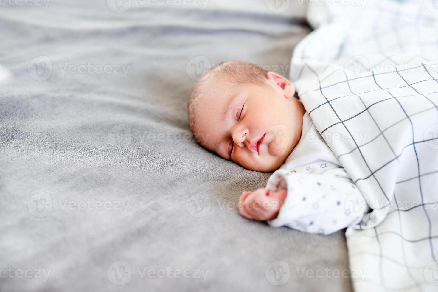 Peaceful baby lying on a bed while sleeping in a bright room. photo