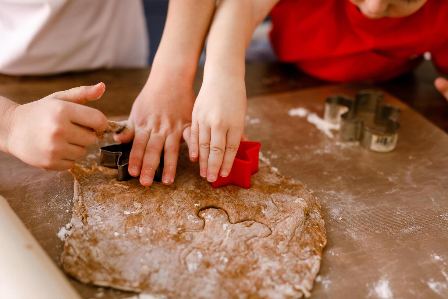 Close-up of children's hands cutting cookies with a cookie cutter on gingerbread dough photo