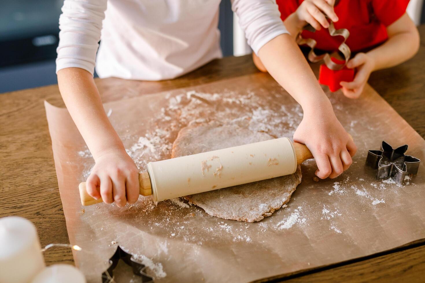Close-up of children's hands cutting cookies with a cookie cutter on gingerbread dough photo