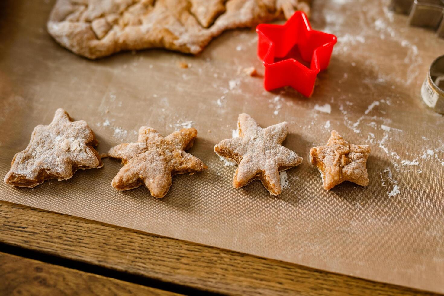 Close-up of children's hands cutting cookies with a cookie cutter on gingerbread dough photo