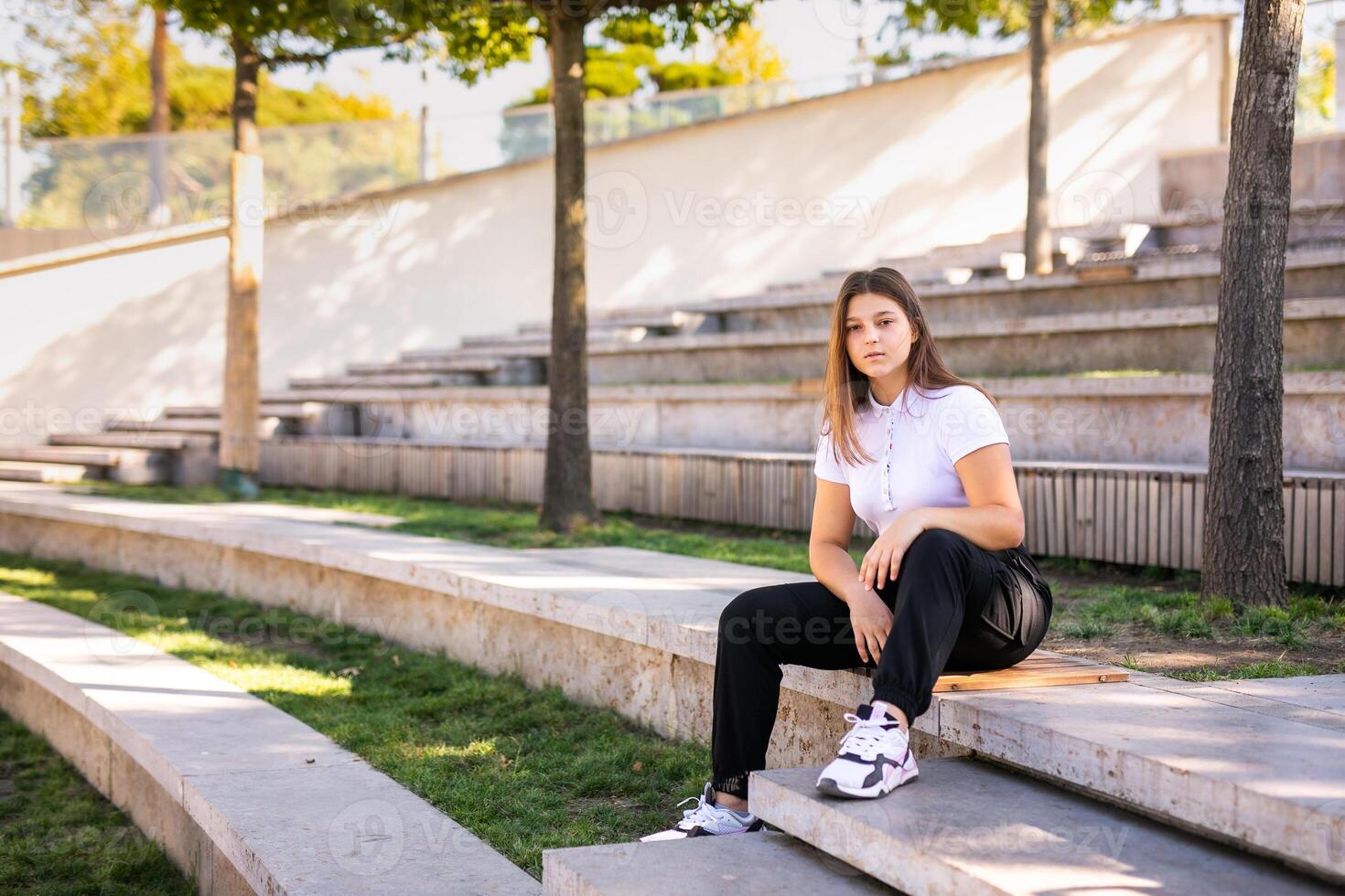 A 16-year-old girl in a school uniform sits on the steps of the street photo