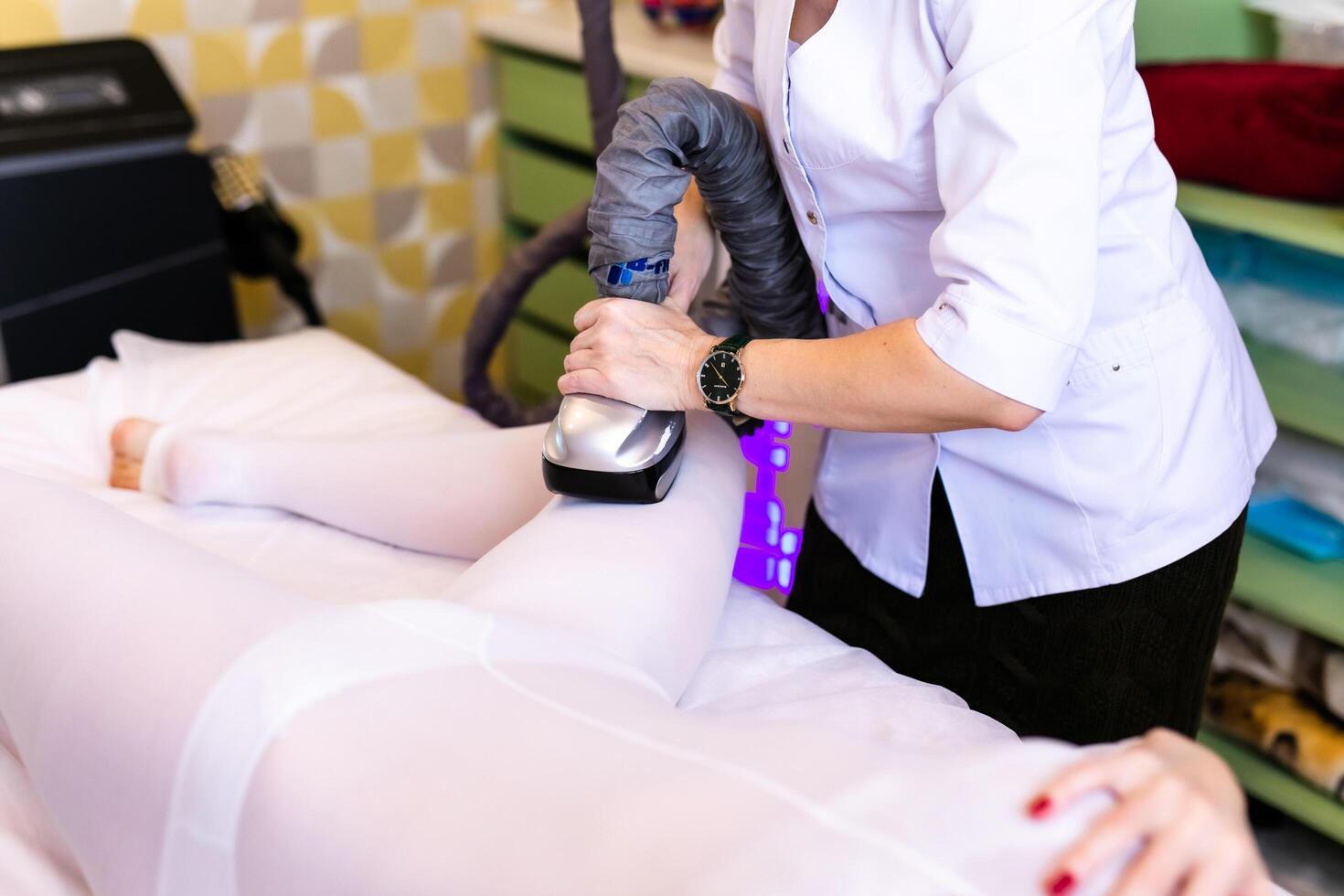 A female masseur gives an LPG massage to an attractive woman in a special white suit in a modern Spa photo