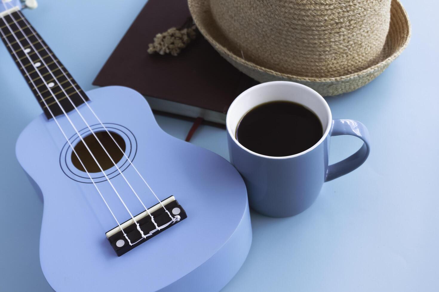 Blue ceramic cup with black coffee put beside Ukulele photo