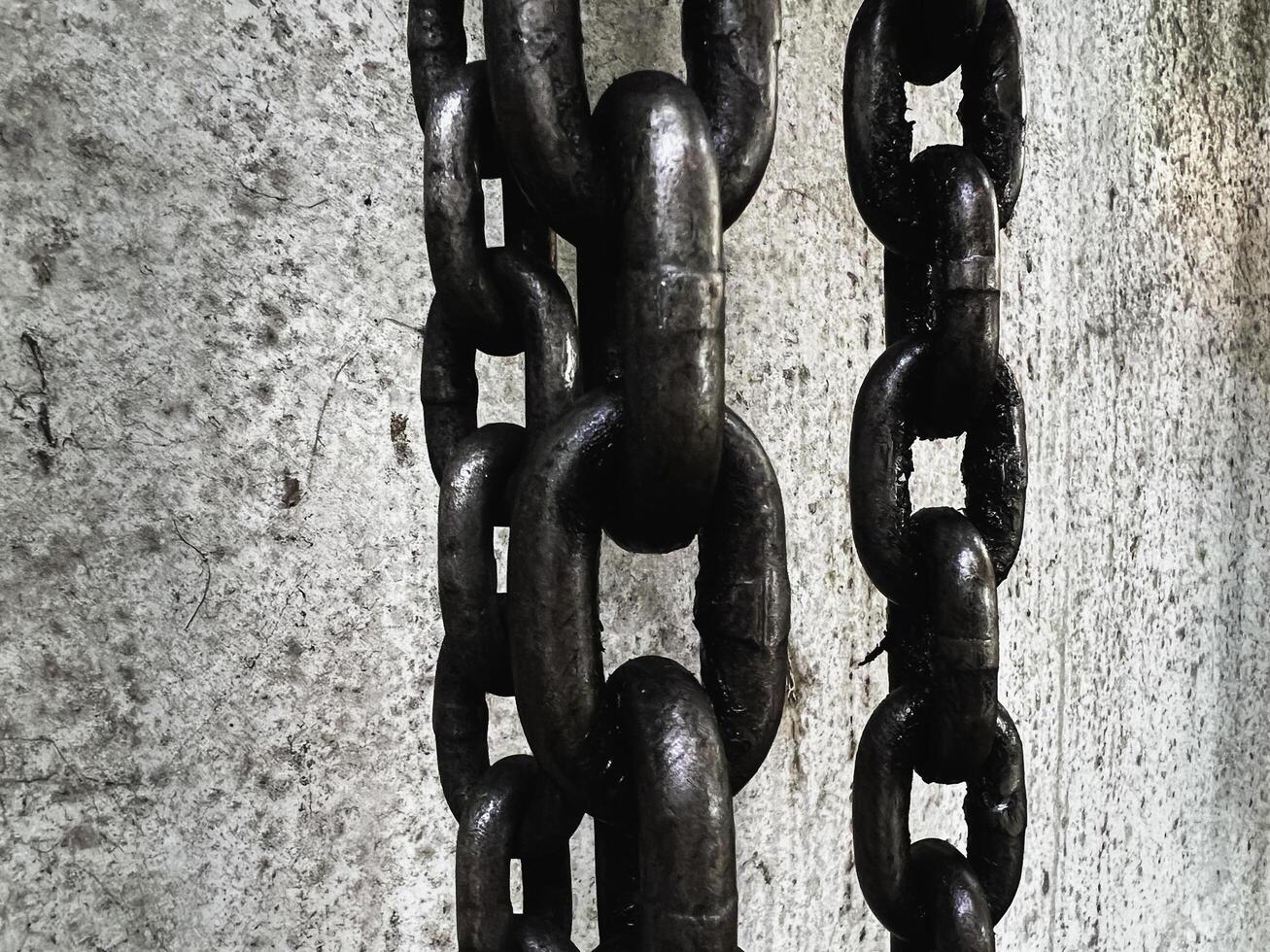 Old and rust iron chain hanging on wall, photo