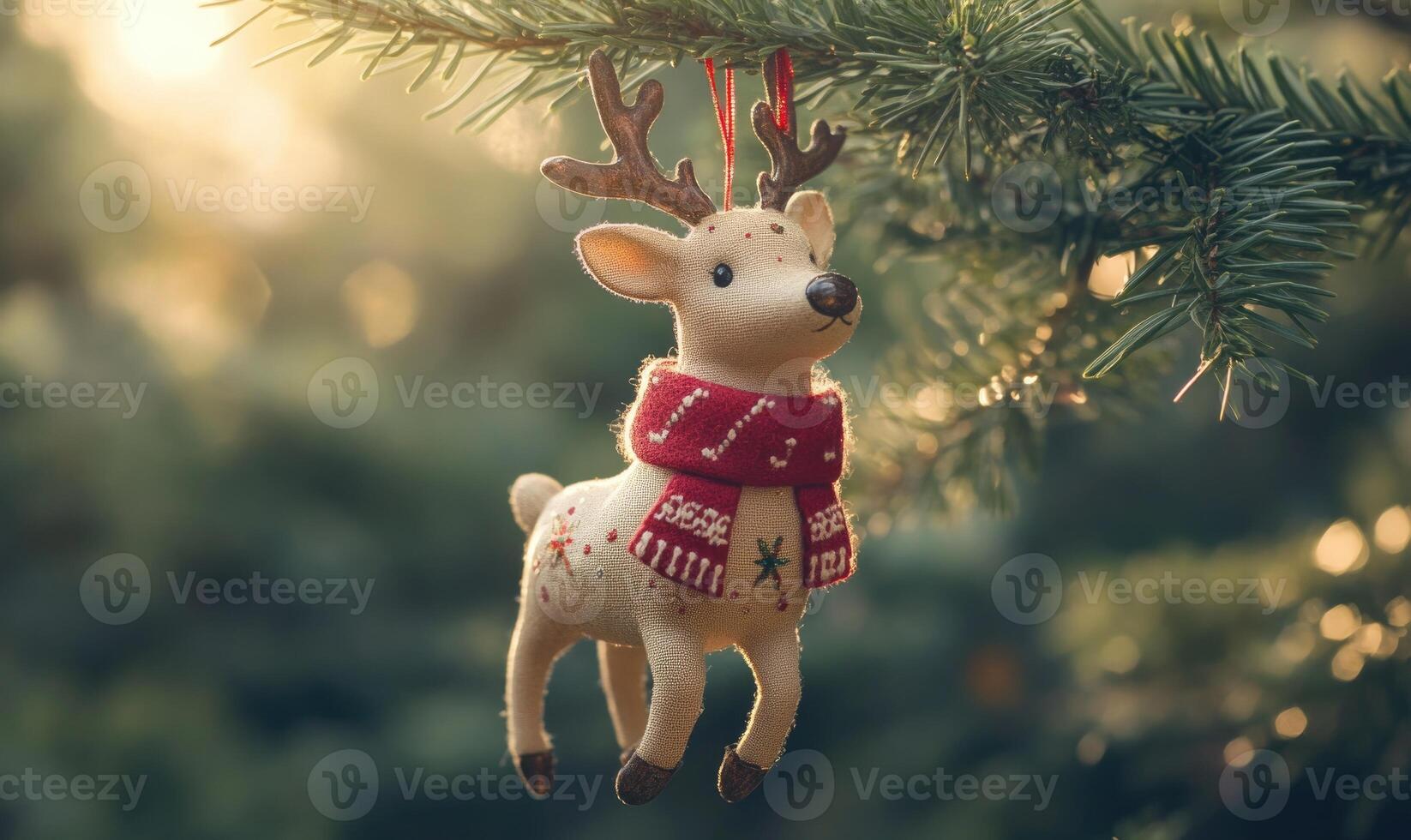 A white deer ornament with a red scarf is hanging from a tree photo